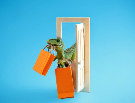 Cute green dinosaur with shopping bags on a blue background. Cute humor shopping concept.の写真素材