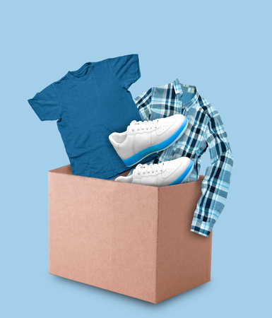 Clothes and shoes in cardboard box on blue background. Minimal collage.の写真素材