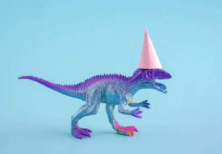 Cute blue dinosaur wearing pink party hat on blue background. Funny idea for birthday card.の写真素材