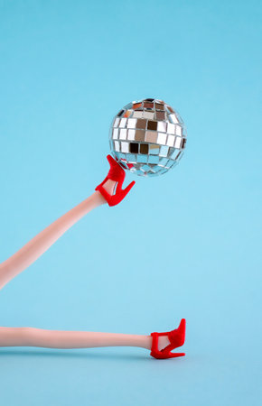 Doll legs in red shoes with disco ball on blue background.の写真素材