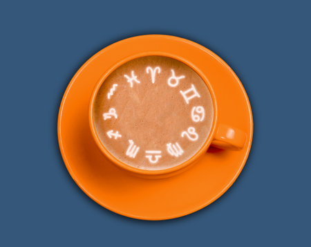 Top view coffee cup with horoscope signs made from milk foam on blue background. Astrology concept.の写真素材
