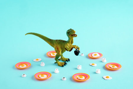 Green dinosaur with fried eggs and coffee cups on blue background.の写真素材