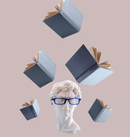 Plaster statue head wearing blue glasses with levitating book. Education concept.の写真素材