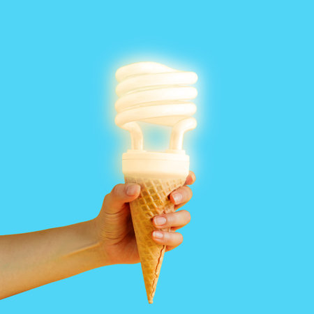 Female hand holding waffle cone with illuminated lamp on blue background.
