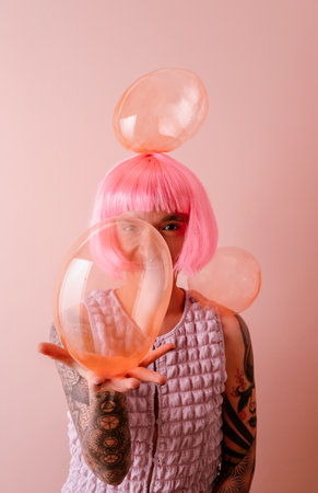 Young beautiful woman with pink hair is laughing and holding soap bubble.