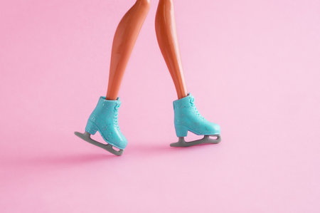 Legs of plastic doll in skates on pink background.の写真素材