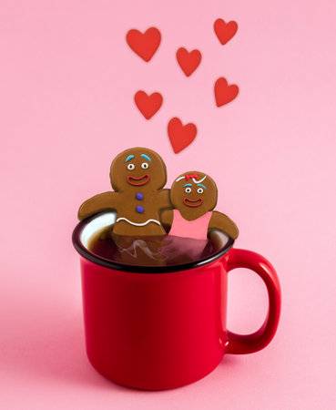 Happy gingerbread man and woman hugging each other inside red mug with warming beverage on pink background. Cute festive card for Christmas and St. Valentines day.の写真素材