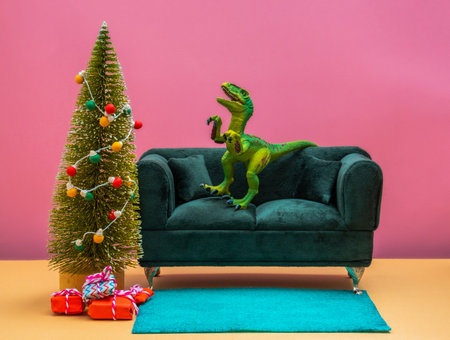 Green dinosaur on couch in living room with Christmas tree. Cute winter holidays card idea.の写真素材