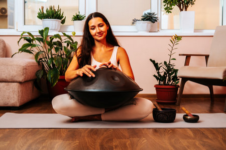 Beautiful young woman playing handpan musical instrument. Sound healing concept.の写真素材