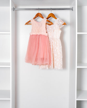 White and pink puffy dresses hang on hangers in modern white dressing room.の写真素材