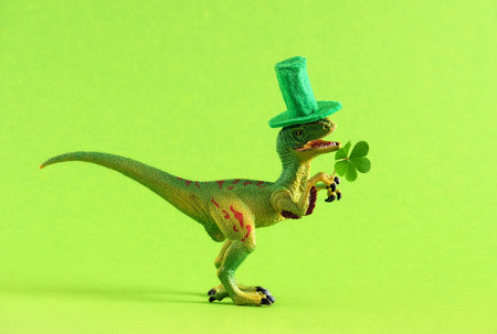 Green dinosaur in green hat holds leaf of clover. Wide banner. Copy space.の写真素材