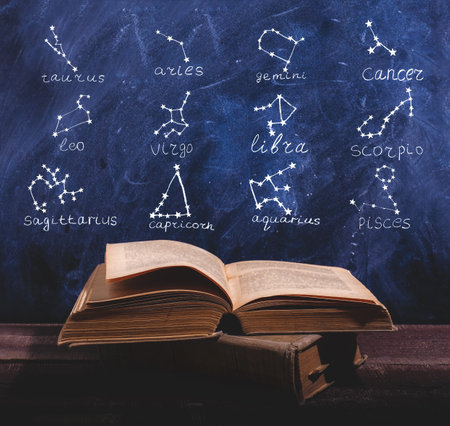 Old book with horoscope constellation above itの写真素材