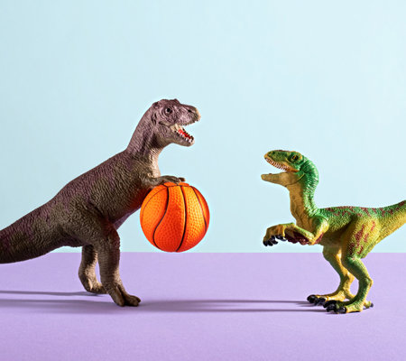 Two dinosaurs playing basketball on blue and violet background.の写真素材
