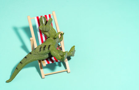 Top view lazy relaxed dinosaur sitting in beach chair on blue background.の写真素材