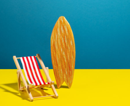 Beach chair and surf board on blue and yellow background.の写真素材