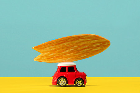 Cute little car with surfboard on blue and yellow backgroundの写真素材