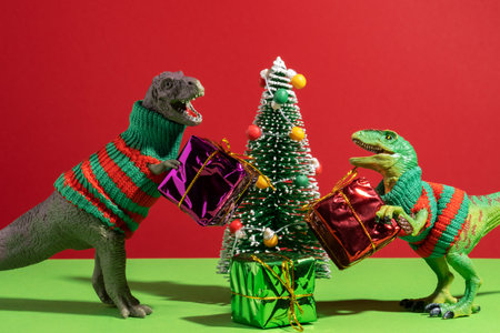 Cute dinosaurs give each other gifts on red and green backgroundの写真素材