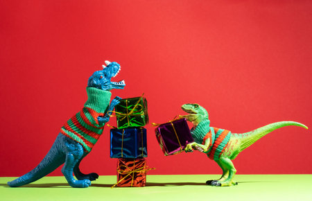 Cute dinosaurs give each other gifts on red and green backgroundの写真素材