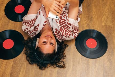 Woman lying on floor with headphones, vinyl records and phone.の写真素材