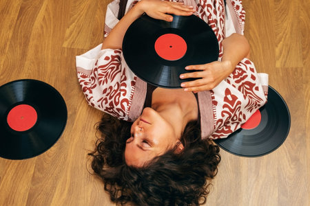 Top view woman lying down on the floor with and listening to old vinyl records.の写真素材