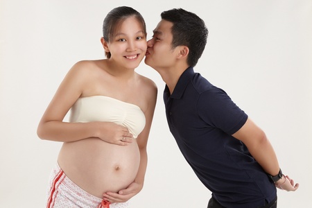 A happy husband is kissing his pregnant wifeの写真素材