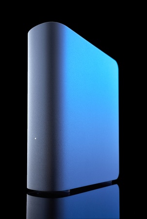 A grey external hard drive with blue highlight against a black background shot on low angle  Reflection on the bottom の写真素材