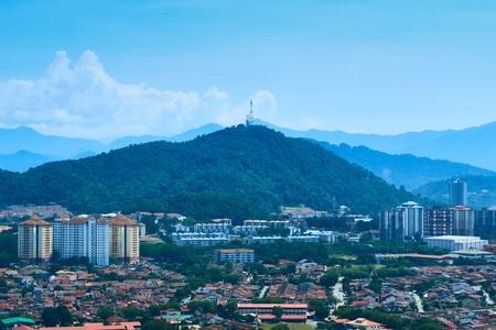 The image shows a wide angle view of Ampang, a suburb near to Kuala Lumpur, Malaysia. It has a housing area and apartments. Tall, lush green mountains serve as a backdrop to the low density suburb.の写真素材