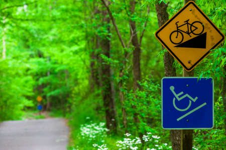 Bike down hill and up hill handicap warning sign along a park pathway.の写真素材