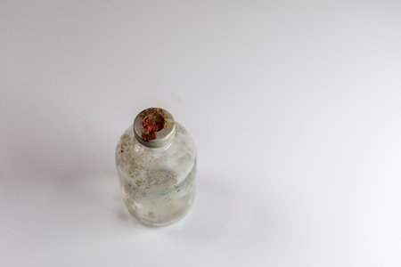 One dirty clear glass medical vaccine bottle, aged and patina on a white background.  Empty and covered with dirt and rust.の写真素材