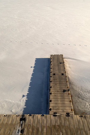 Abstract photo of an iced over boat dock on a Frozen lake covered in snow with animal tracks.の写真素材