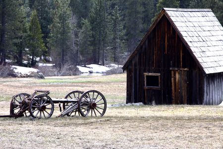 old wooden wagon in a field in front of a barnの写真素材