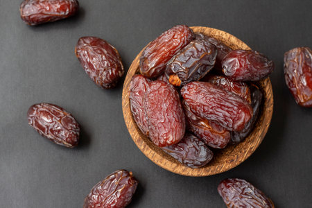 delicious dates in a wooden bowl on a black background, high angle viewの写真素材