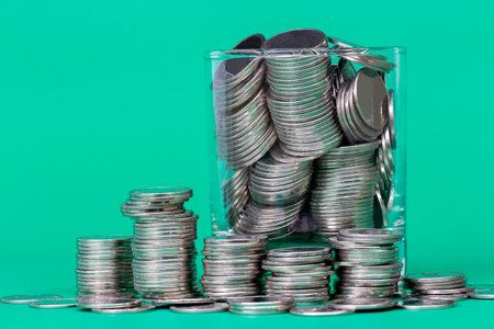 Stack of Coins in a glass jar and outside on a green background, business and finance concept