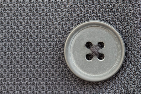 Vintage metal sewing buttons sewn on dark gray knit fabric background close up