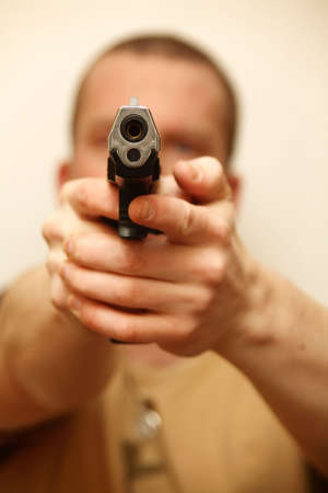 A man holding a pistol and pointing it at the camera.