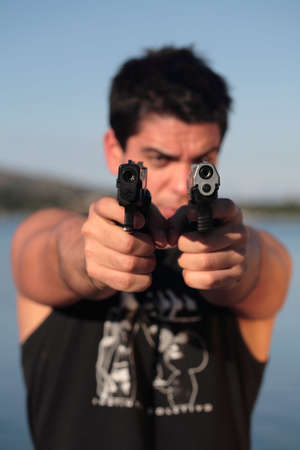 A man holding a pistol and pointing it at the camera. (This image is part of a series).の写真素材