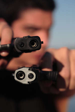 A man holding a pistol and pointing it at the camera. (This image is part of a series).の写真素材