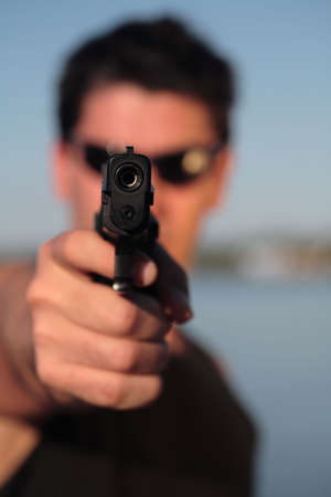A man holding a pistol and pointing it at the camera. (This image is part of a series).の写真素材