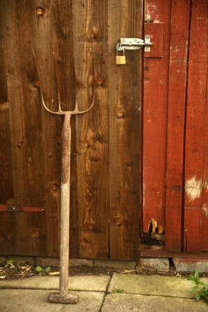 A pitchfork laying against an old wooden door.の写真素材