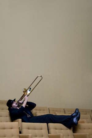 A trombonist in a black suit and yellow background.の写真素材