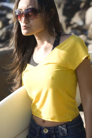 An asian surfer woman wearing a yellow top and jean skirt.の写真素材