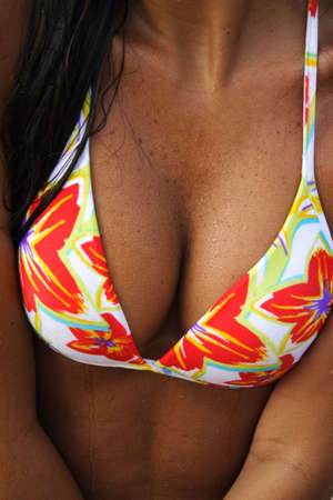 A sexy tanned girl's breasts wearing a flowered bikini at the beach.の写真素材