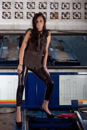 A young brazilian female model shot in a dirty auto repair shop.の写真素材