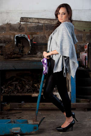 A young brazilian female model shot in a dirty auto repair shop.の写真素材