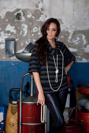 A young brazilian female model shot in a dirty auto repair shop.の写真素材