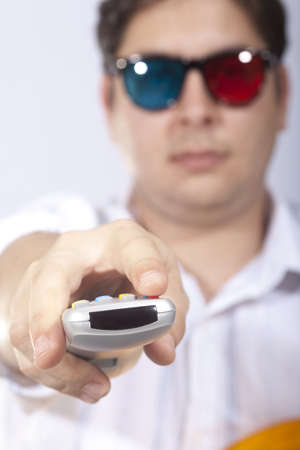 A young man watching a movie in 3D, with stylish 3D glasses and eating popcorn.の写真素材