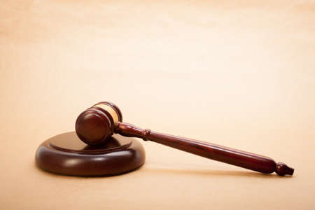 A wooden gavel and soundboard on a light brown background.の写真素材