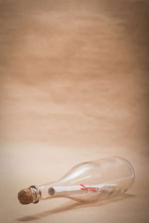 A message inside a glass bottle, isolated on a sand color background, in a studio shot.の写真素材