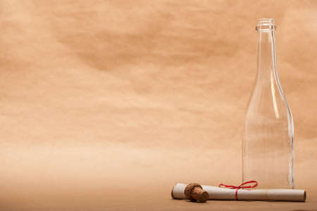 A message next to a glass bottle, isolated on a sand color background, in a studio shot.の写真素材
