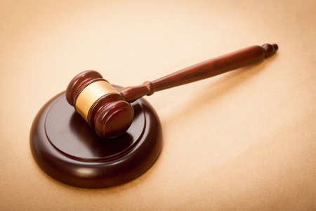 A wooden gavel and soundboard on a light brown background.の写真素材